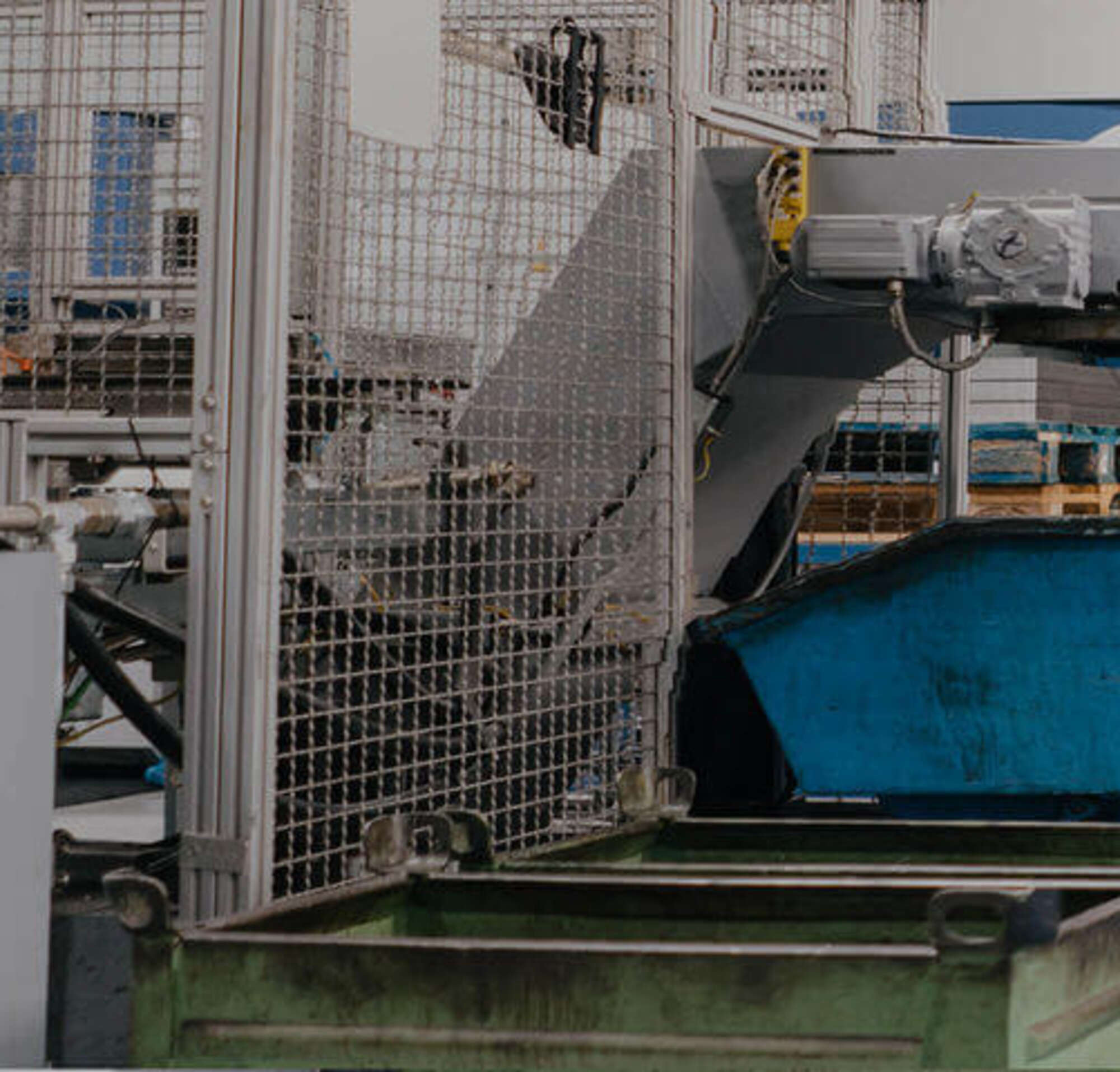 A man in a suit walking with a factory worker inside a factory with big machinery.