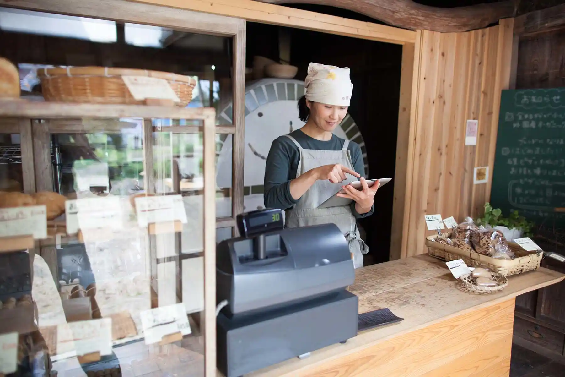 タブレットで売り上げをチェックするカフェオーナー