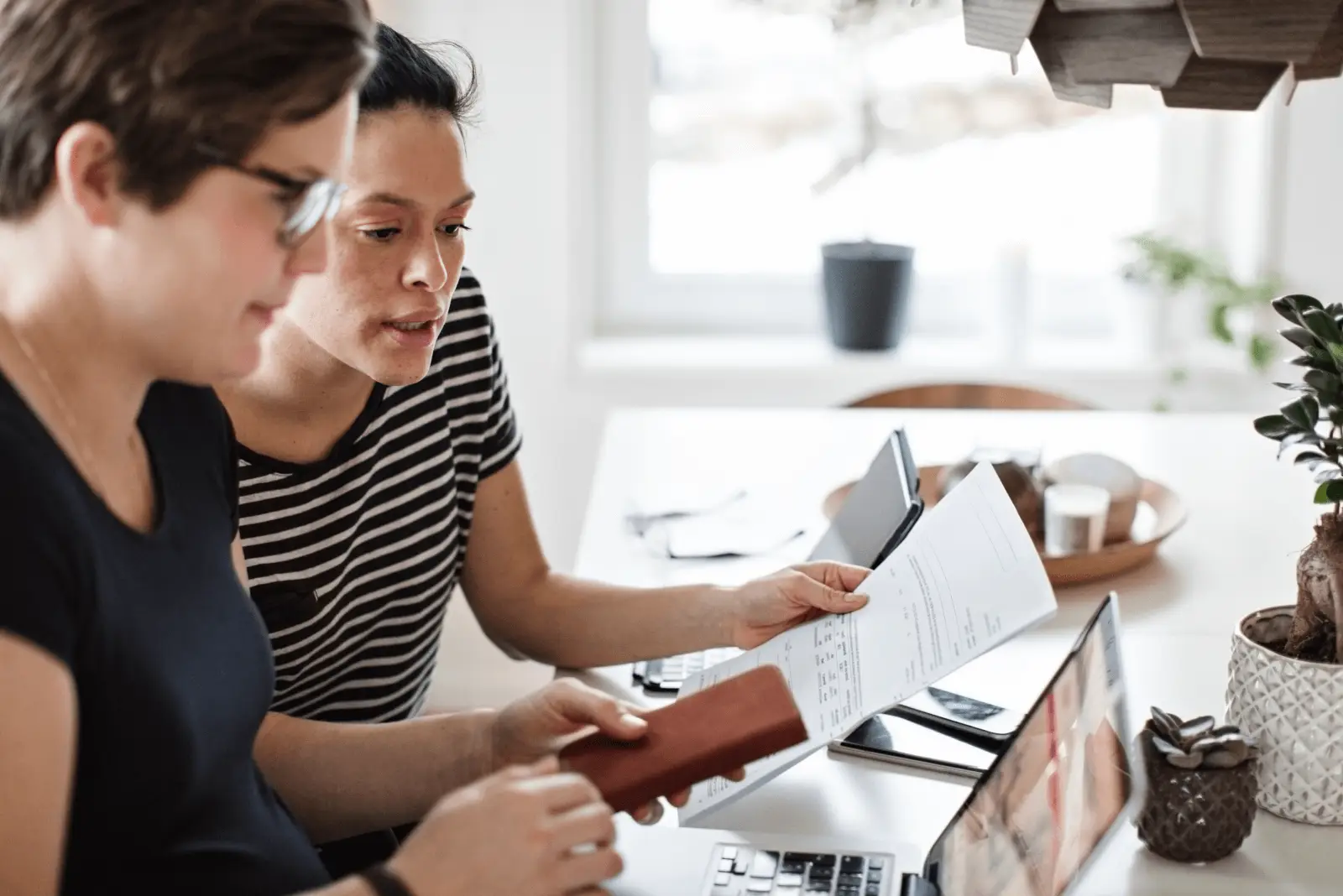 Two insurance employees review a document and look at an insurance agreement on a computer