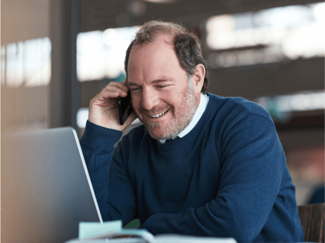 Person smiling on the phone looking at their laptop