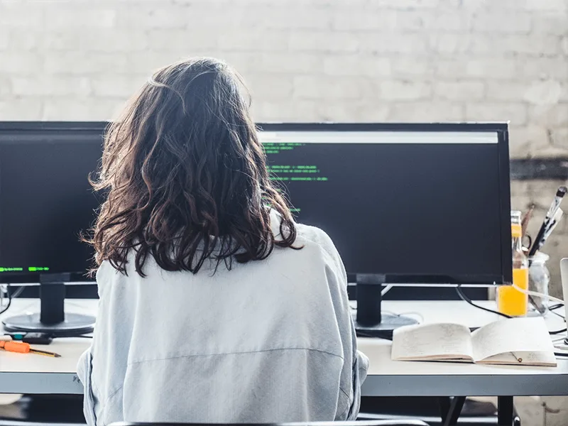 Woman at a work station with two computer monitors