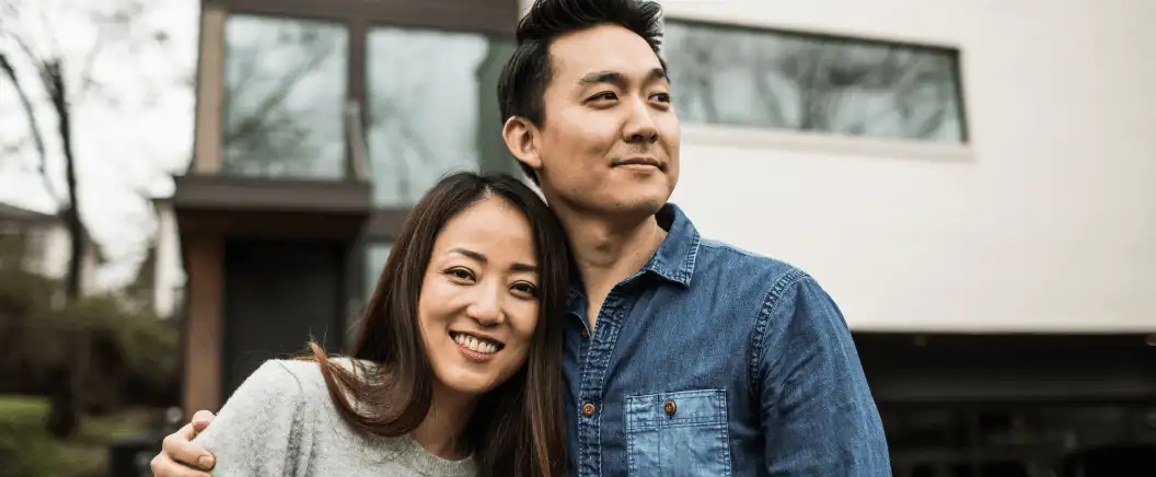 Two homeowners with insurance stand in front of a house