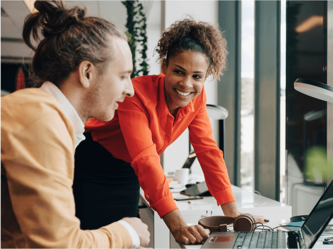 Two people working together on a laptop at a desk