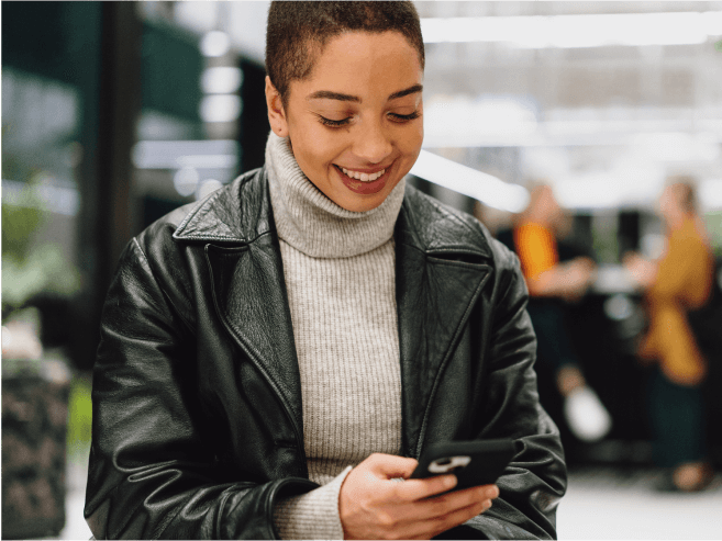 Person smiling outside while looking at phone