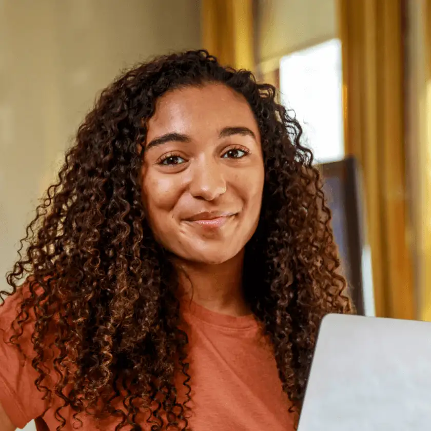 Person smiling holding up a laptop